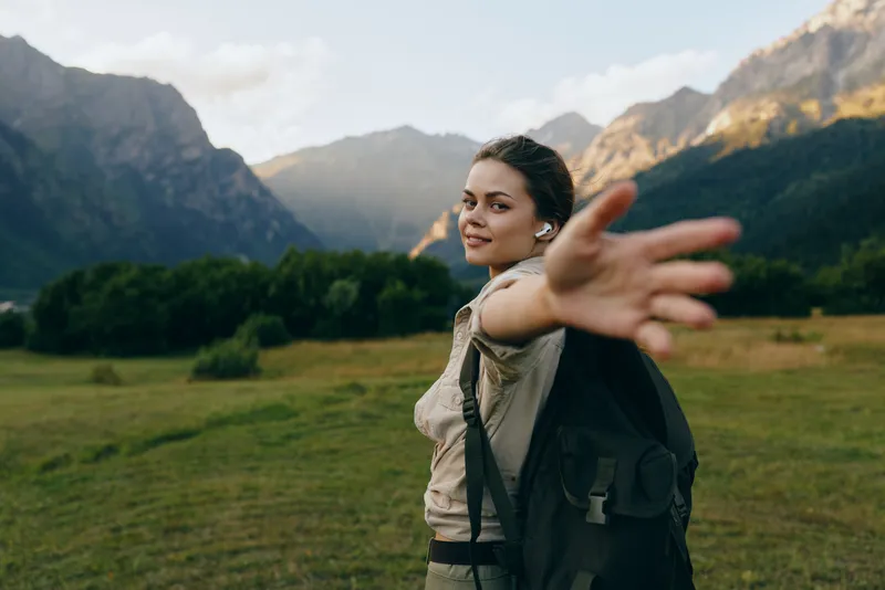 Woman with backpack outdoors in a wide mountain landscape, exuding freedom and adventure, ready for travel and outdoor exploration amid nature and scenic valley