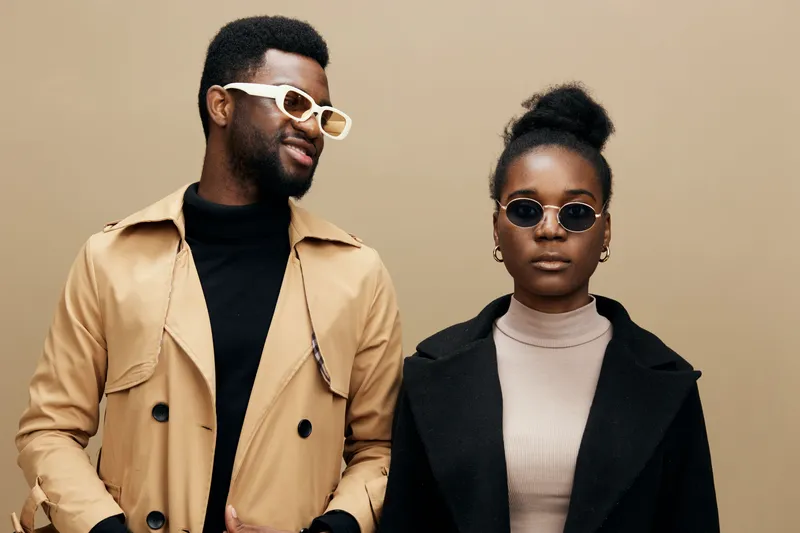 Stylish African American couple in fashionable sunglasses, showcasing modern fashion trends against a soft beige background