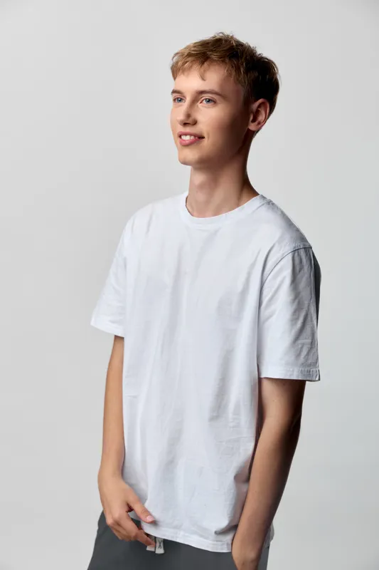Casual, young man in a white tshirt posing in a studio, relaxed stance, minimalist fashion, clean background, soft light, versatile wardrobe for everyday style
