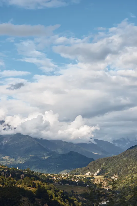 Mountain landscape valley and village under dramatic clouds panoramic nature scene with rolling hills and forest