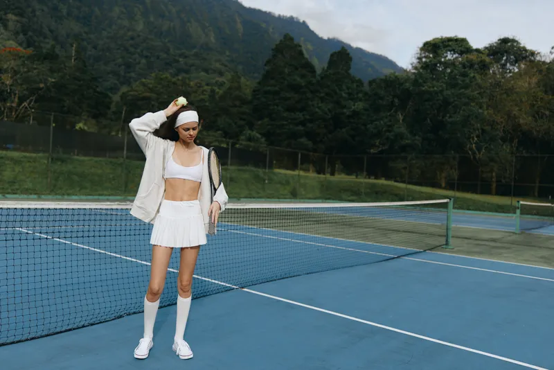 Young athletic woman in sportswear enjoying tennis outdoors, showcasing confidence and vitality on a sunny day, perfect for sports and lifestyle concepts