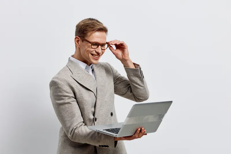 smiling man holding laptop wear gray checkered suit glasses looking at screen isolated on light background digital nomad technology concept