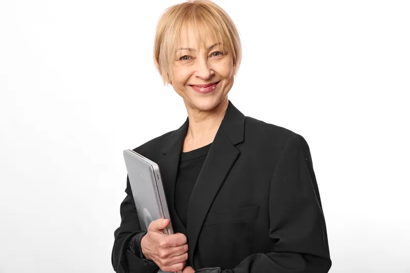 elderly woman book smiling suit portrait white background, professional senior holds a book, calm friendly smile, closeup studio headshot, isolated on soft clean white backdrop