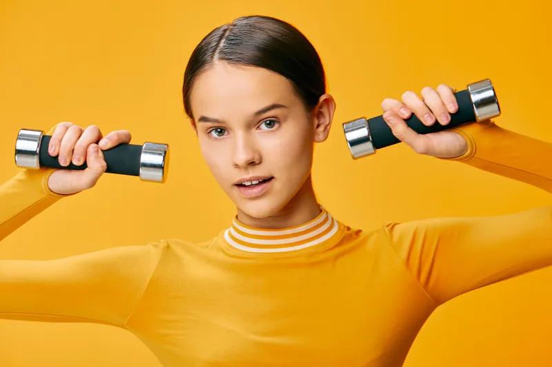 Fitness, woman, sport, weights, workout, training, athletic, exercise, gym, health in a bright studio as she lifts dumbbells, showcasing strength, balance and determination during a focused training
