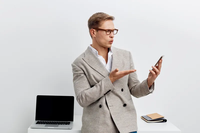 surprised man using smartphone with laptop on white table communication digital nomad cybersecurity concept
