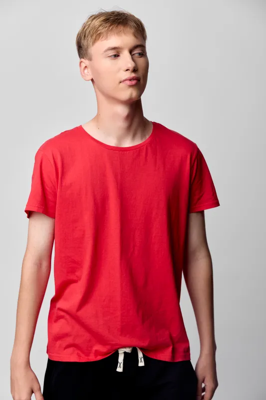 Young man wearing a red t shirt in a studio setting, casual wear and fashion mood, relaxed pose with clean backdrop, suitable for lifestyle and apparel themes