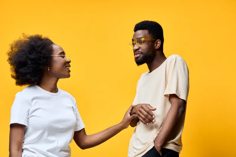 Happy young couple enjoying each other s company, dressed in casual clothes against a bright yellow background, showcasing joy, connection, and warmth