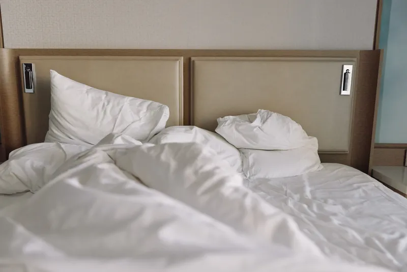 Bed, bed sheets, pillows and headboard form a calm bedroom scene with soft white linens, offering restful relaxation and clean, minimal comfort for sleep.