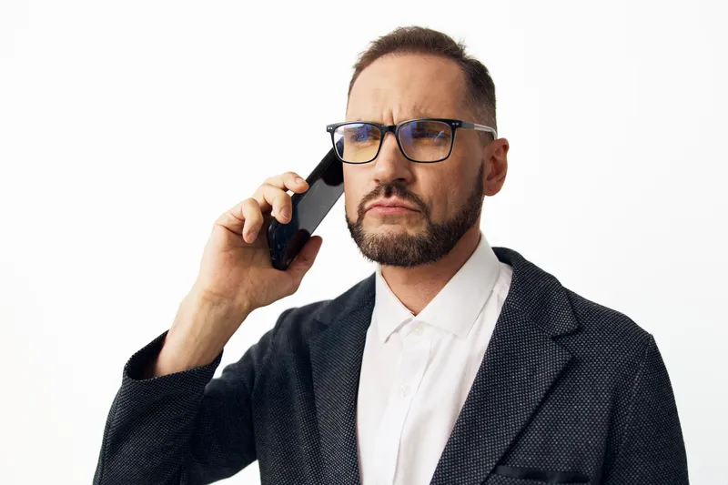 Professional man on a call, exuding confidence and focus. A polished executive in a blazer and shirt, framed against an isolated white background, conveying determination and goal driven
