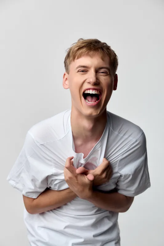 Laughing man in a white shirt in a studio setting, energetic, joyful, expressive, capturing candid mood for lifestyle, fashion, or marketing visuals
