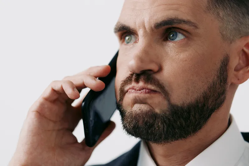 A business professional man speaks on a mobile phone, exuding focus and determination, against an isolated colored background that highlights modern work life.
