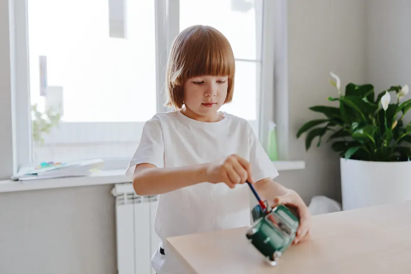 Young boy engaged in creative play, working with toys and exploring imagination in a bright, cheerful indoor space filled with greenery and natural light.