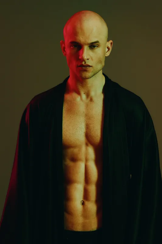 Strong man with a focused expression, wearing a dark robe, captivating lighting creates a dramatic atmosphere. This image highlights strength and confidence.