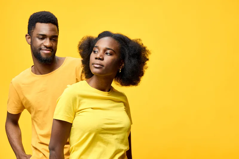 A vibrant portrait of a young African couple wearing matching yellow t shirts, showcasing joy and connection against a bright yellow background