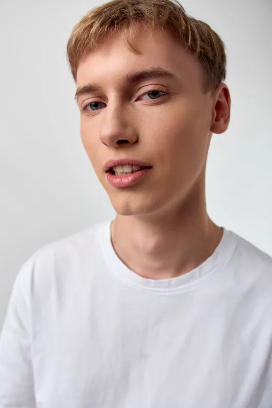 Young man, casual, white t shirt, close up, facial expression with calm gaze and soft light reveals a clean, approachable vibe in a studio shot