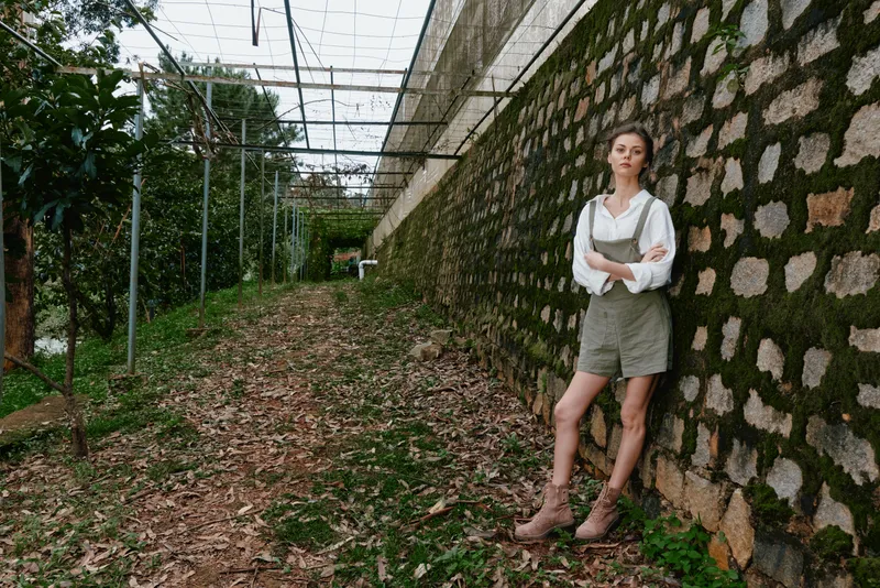 Young woman in casual green outfit stands on a seasonal path surrounded by greenery, exuding confidence and serenity, perfect for lifestyle and nature themes