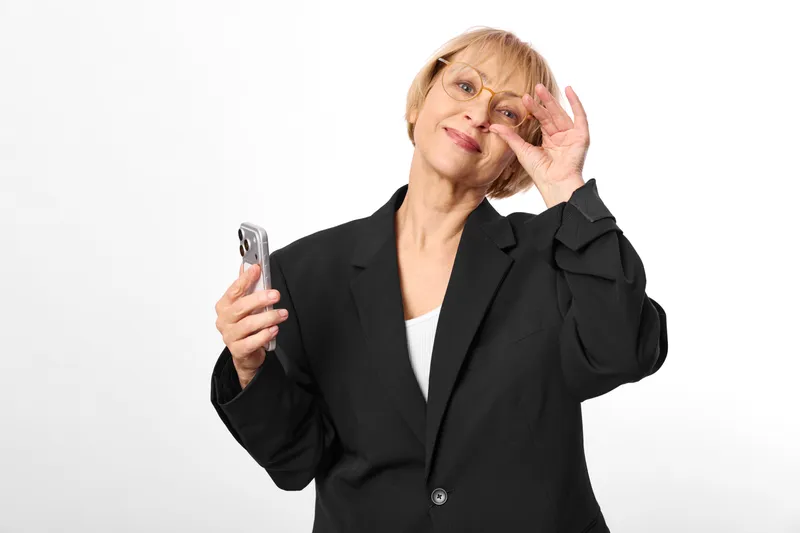 Senior woman smartphone communication technology business glasses smiling studio isolated, on white background, holding phone and touching eyeglasses, gesture for modern life