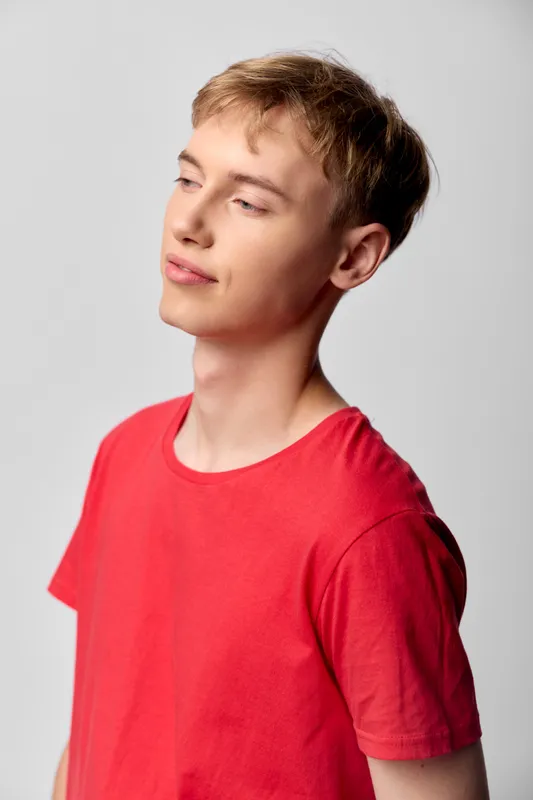 Youth, boy, red, shirt, thoughtful, casual, studio, pose, expression and a calm studio setting with soft lighting highlights confident, relaxed mood in a modern fashion oriented image