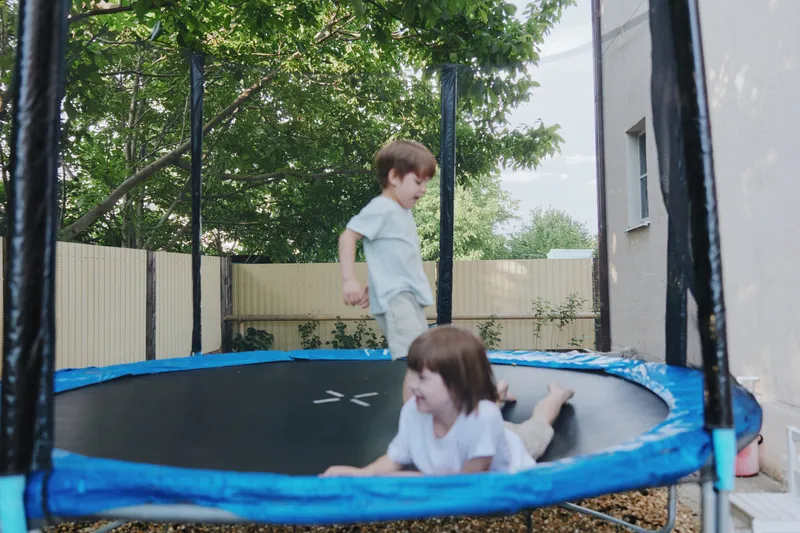 Happy children playing on a trampoline, enjoying a sunny day outdoors in a backyard setting. Their laughter fills the air with joy and excitement.