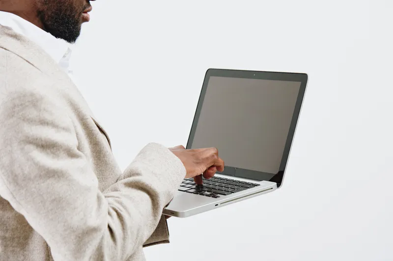 Modern man working on laptop computer in minimalistic office environment, close-up of hands and device, professional workplace setting, technology, communication, workplace tools, versatile work scene
