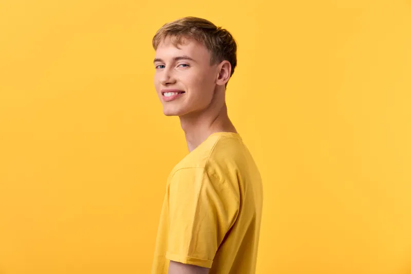 Yellow background with a smiling young man wearing a casual shirt, vibrant studio scene conveying optimism, energy and approachable style suitable for lifestyle fashion and branding projects