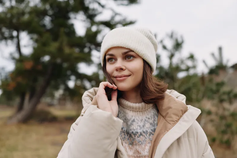 Woman in a cozy winter coat and beanie, outdoors in a calm park, soft light and thoughtful smile, seasonal fashion portrait in natural scenery