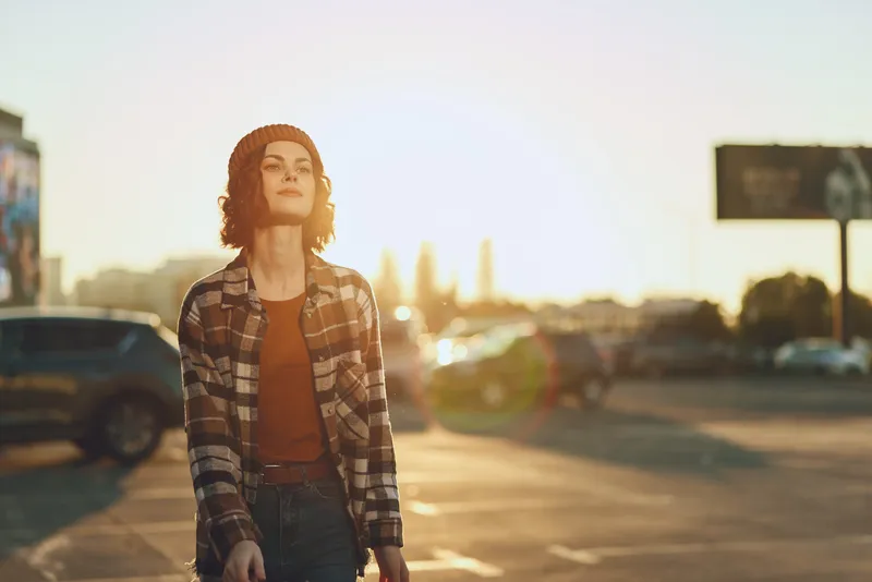 woman walking in urban street at golden hour, sunlight backlight and beanie style, confident candid portrait capturing authenticity, mindful living and emotional storytelling with golden hour glow