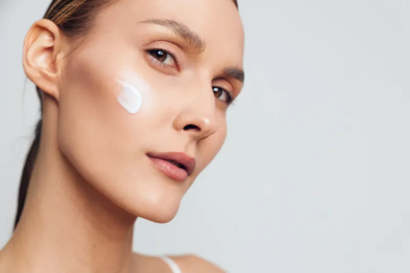 Woman in closeup applying white face cream to cheek, smooth skin and beauty skincare, wellness and selfcare routine, gentle spa care daily