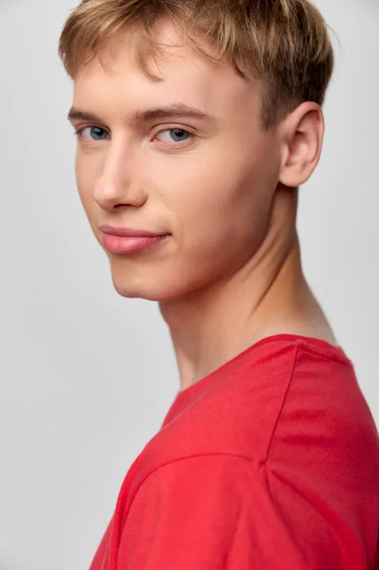 Close up of a young man in a red shirt, confident gaze, soft studio lighting, clean background, casual style, front pose, highlighting youth and contemporary appearance