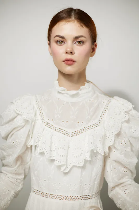 Portrait of a young model in a vintage white dress with delicate lace details, exuding calm emotions against a soft neutral background, ideal for fashion and beauty themes
