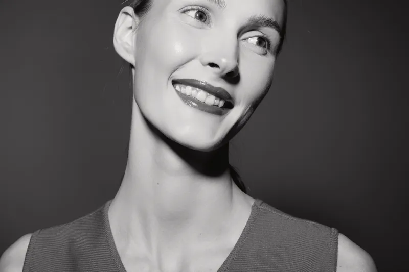 Smiling young caucasian woman with pale skin and sleek hair looks away in black and white portrait. Concept of beauty and happiness.