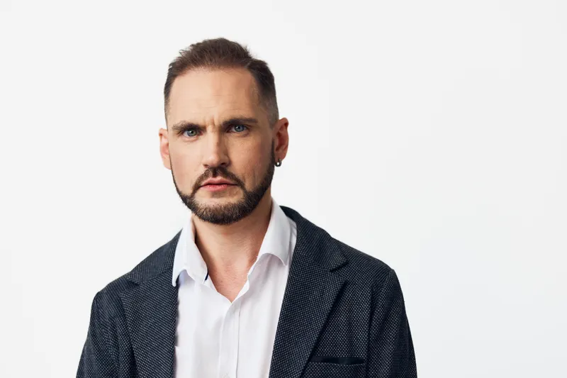 A professional businessman stands before an isolated colored backdrop, exuding calm confidence and leadership, with a focused expression that conveys executive poise and reliability.