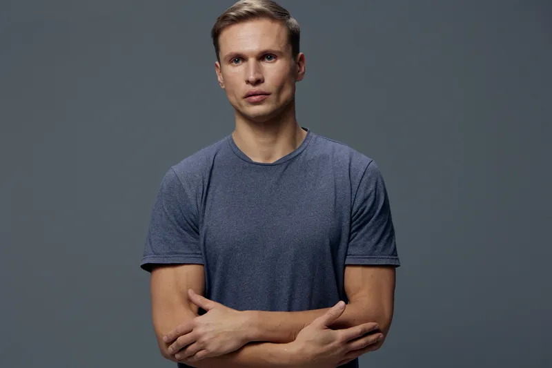 serious man with crossed arms wear casual blue t shirt isolated on grey background studio portrait, digital detox, mental health, technology lifestyle