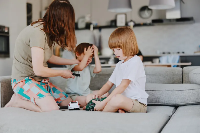 Caring woman playing with her children in a cozy living room, nurturing family bond and joyful interaction, perfect for depicting daily family life.