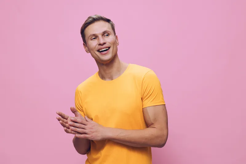 Smiling happy young man wearing yellow t-shirt on pink background studio portrait, cheerful expression, casual style, positive attitude, vibrant colors, lifestyle concept.