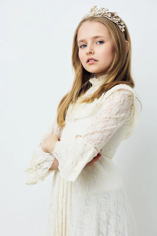 Elegant young girl in a white lace dress with a tiara, exuding a calm and confident expression, perfect for themes of childhood purity and fairy tale aesthetics