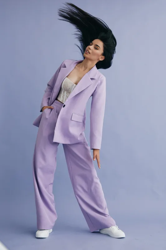 woman in lavender suit dancing with flowing hair, white sneakers, pastel background, fashionable and dynamic pose, elegant outfit