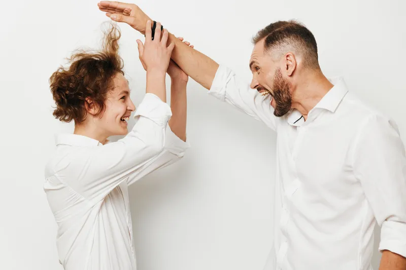 An accomplished business professional and colleague share a joyful high five against an isolated colored backdrop, conveying teamwork, confidence, and positive emotion in a clean corporate setting.