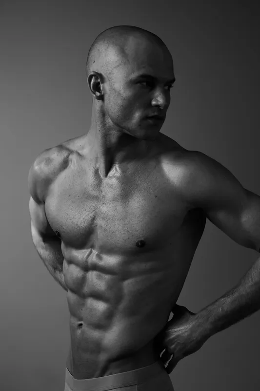 Black and white portrait of a muscular man showcasing strength, confidence, and determination through a powerful expression and dynamic pose.
