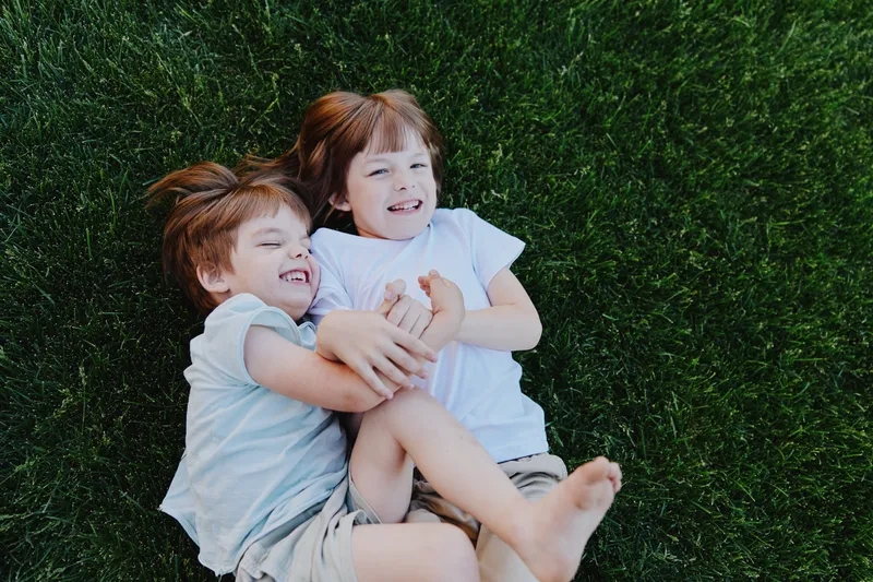 Happy children playing together on green grass, enjoying a sunny day with smiles and laughter. Perfect for family and childhood themes.