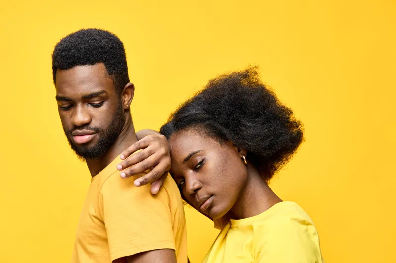 African couple with matching yellow shirts, showcasing love and affection against a vibrant yellow background, expressing emotion and connection