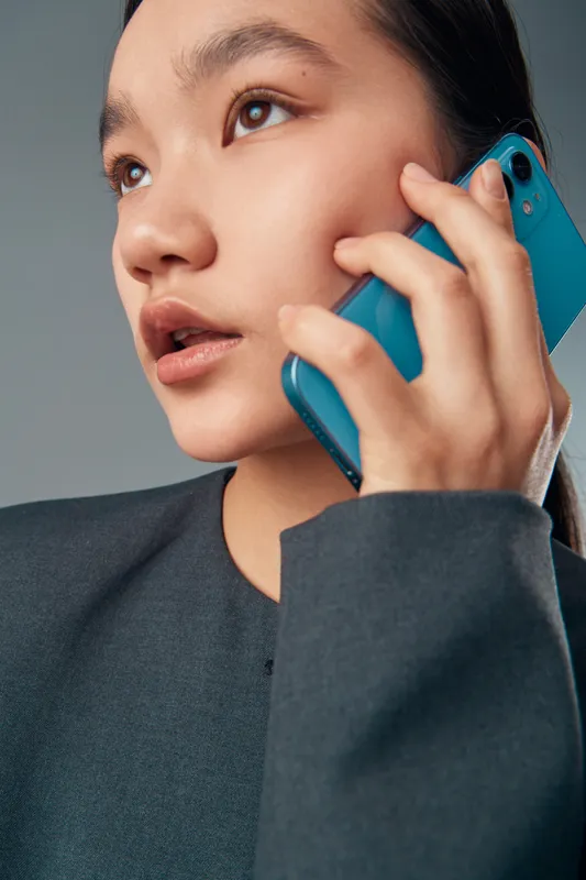 Woman talking on smartphone with focused expression wearing dark clothing, closeup portrait with modern technology and communication in studio setting.