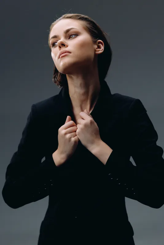 confident woman in black jacket looking up with determined expression and neat hairstyle