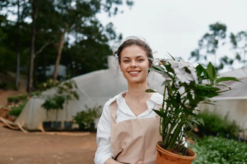 Young woman in garden with potted plant, showcasing joy and nature s beauty in a serene outdoor setting, perfect for promoting gardening and plant care