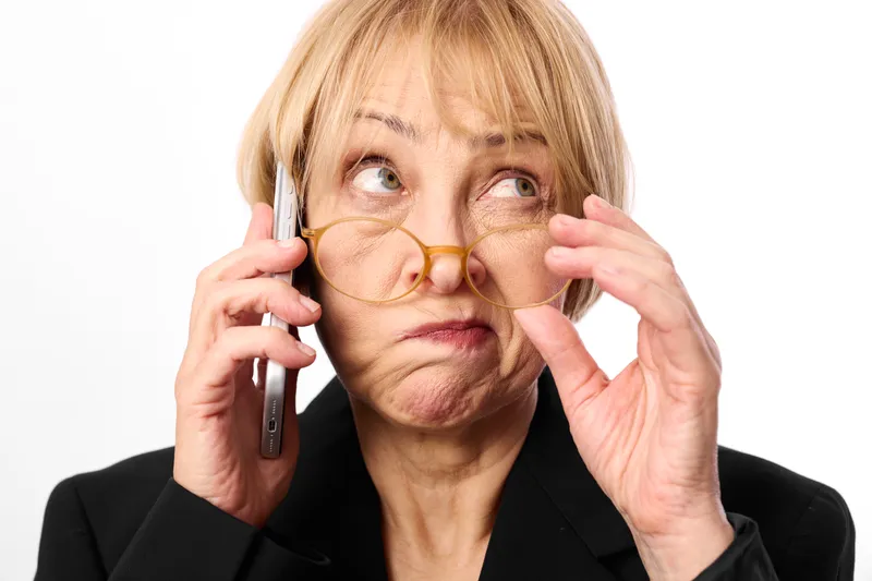 Elderly woman phone glasses surprise portrait isolated white hand calling, senior blonde face with expression, holding smartphone to ear and adjusting spectacles, closeup studio