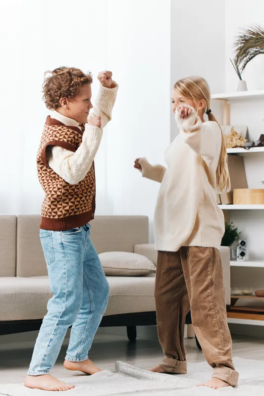 Authentic playful scene of children indoors engaged in an imaginative game, capturing a school vibe at home and a cozy lifestyle moment filled with light and candid smiles.
