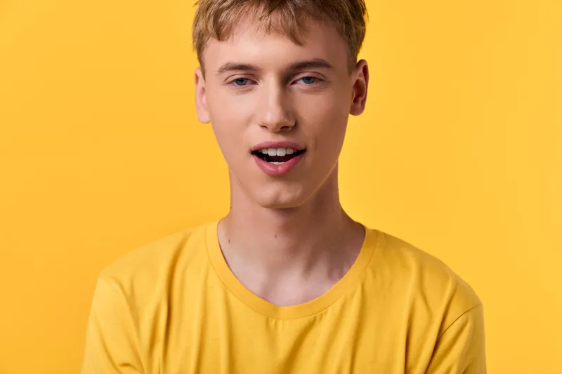 Young man in a yellow shirt against a vibrant yellow backdrop, cheerful expression and casual style, studio shot conveying optimism, bold color harmony and modern mood.
