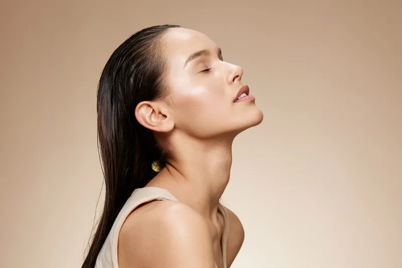 Exquisite portrait of a woman with flawless skin, showcasing a serene expression against a warm neutral background, ideal for beauty and skincare concepts