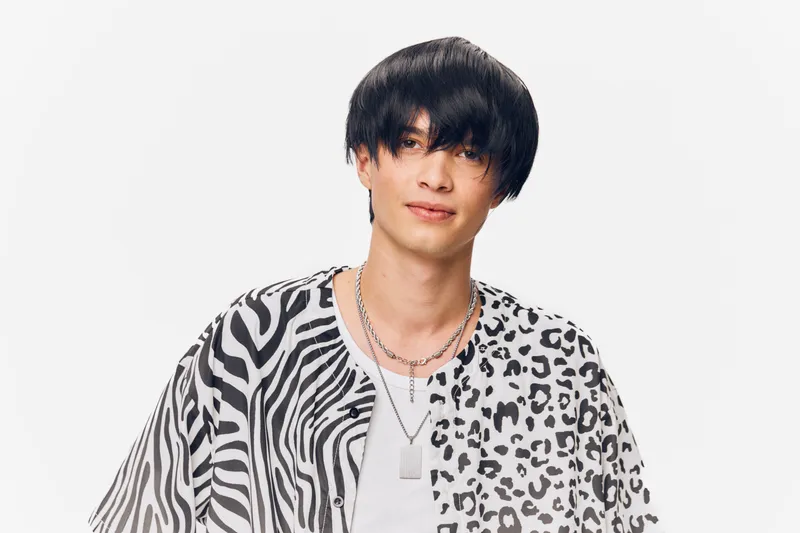 young man with black hair wearing a patterned animal print shirt, casual style, smiling, isolated on white background