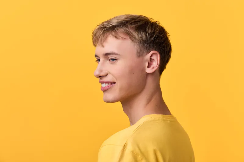 Young man in a yellow shirt against a bright yellow backdrop, showcasing casual style and cheerful vibe for lifestyle, fashion and positive branding imagery